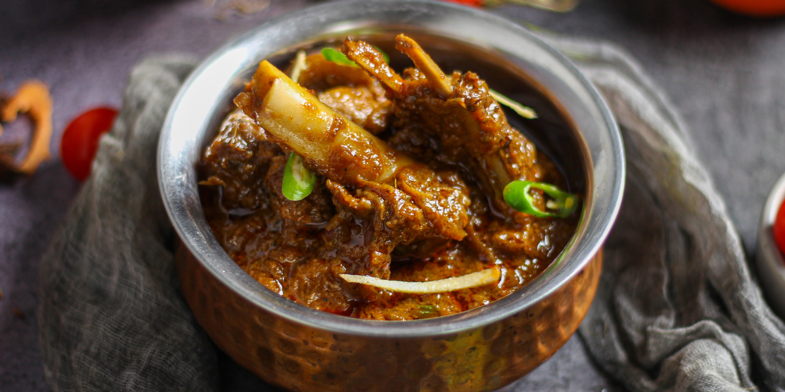 Spiced goat curry in a traditional copper bowl